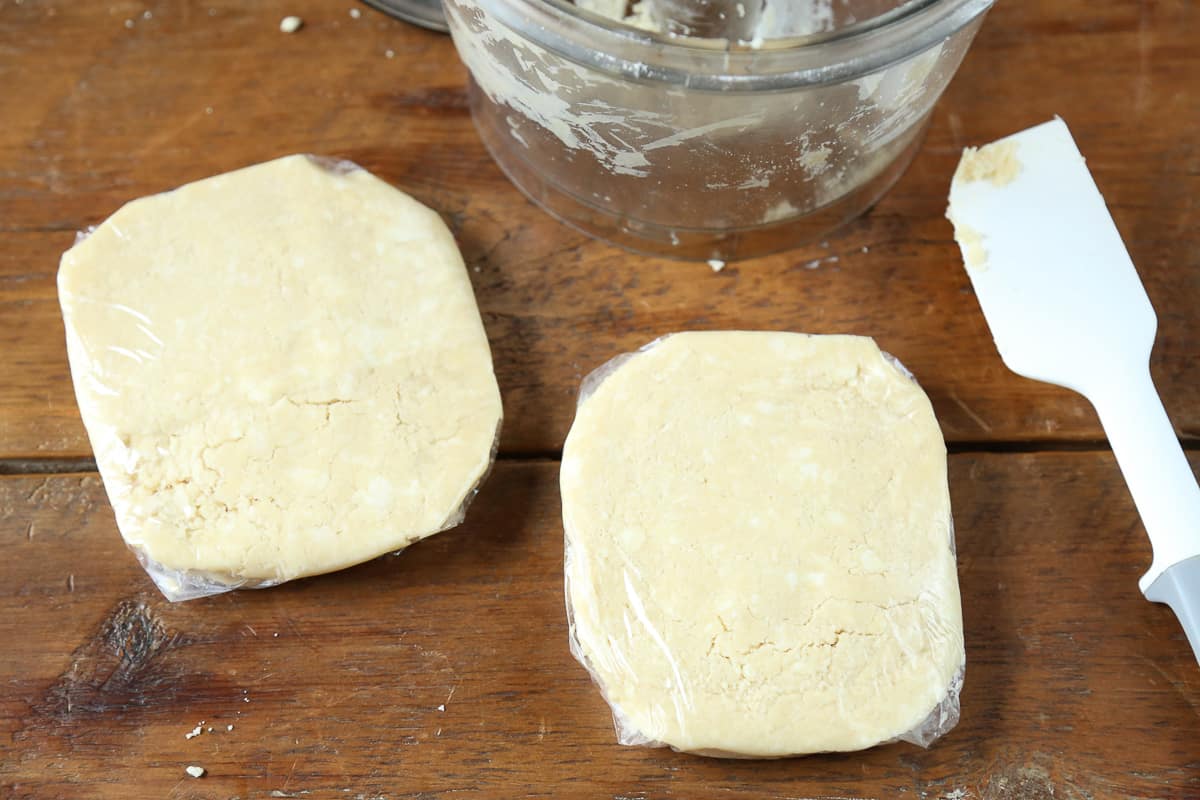 two disks of pie dough wrapped in plastic wrap.