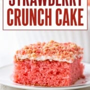 slice of strawberry cake topped with white icing and a golden oreo strawberry topping.