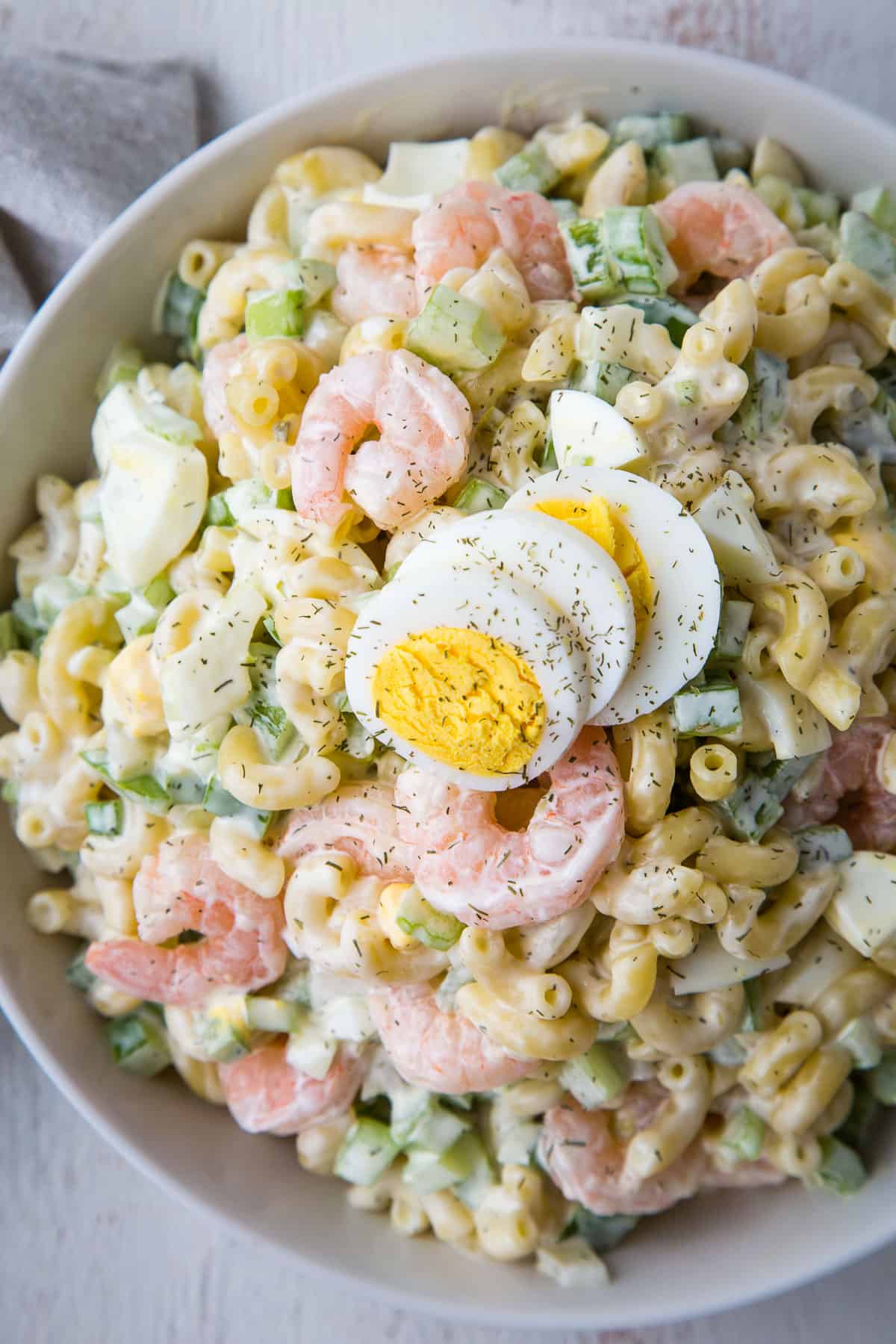 shrimp macaroni salad topped with hard boiled egg slices.