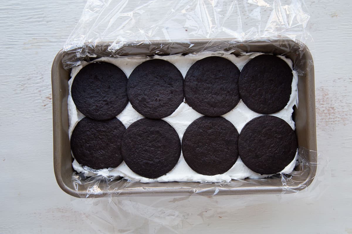 layer of chocolate wafers on top of whipped cream in a loaf pan.