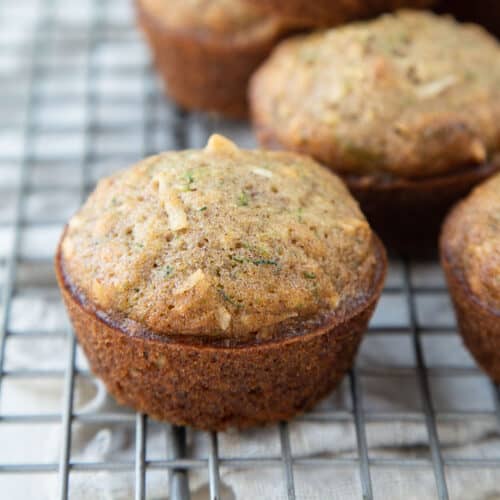 zucchini muffins with coconut and walnuts on a wire rack.