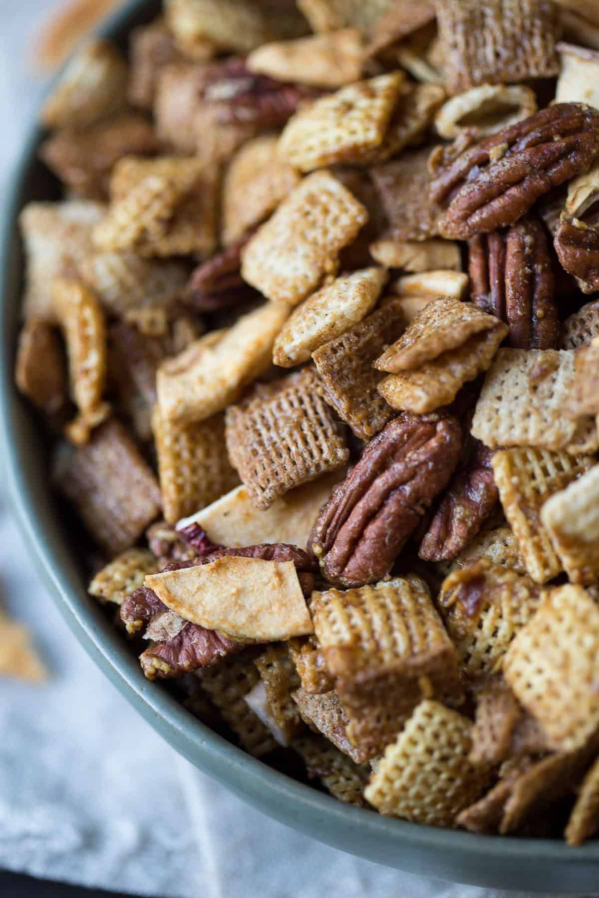 chex cereal, apple chips, and pecans in a green bowl.