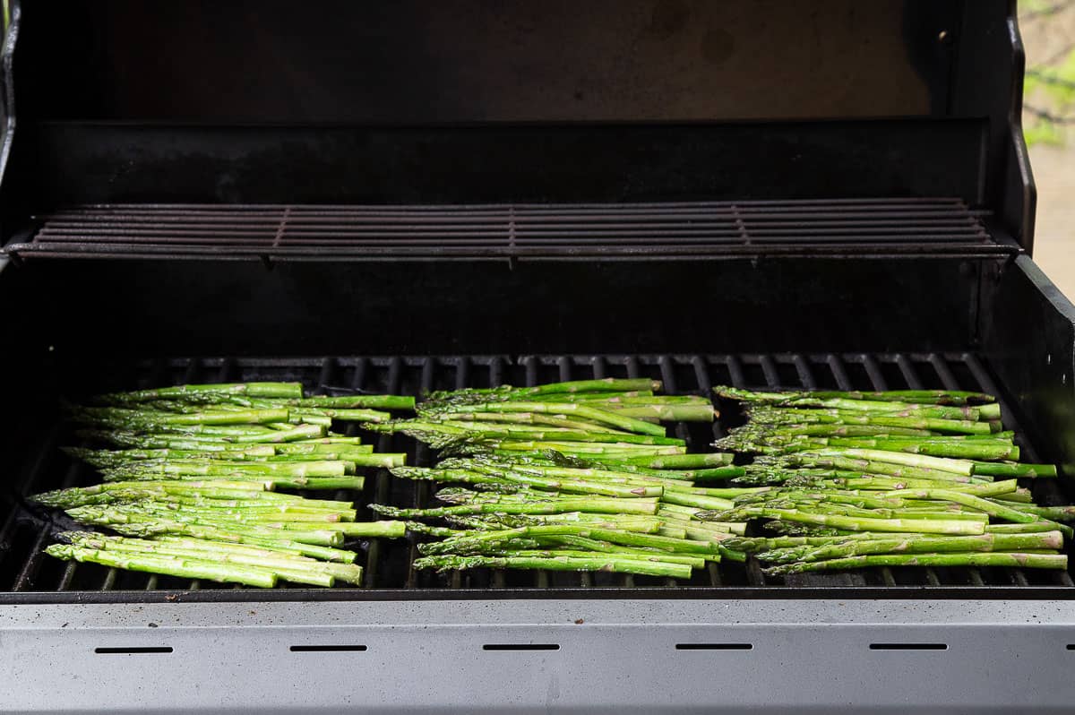 three rows of asparagus on a gas grill.