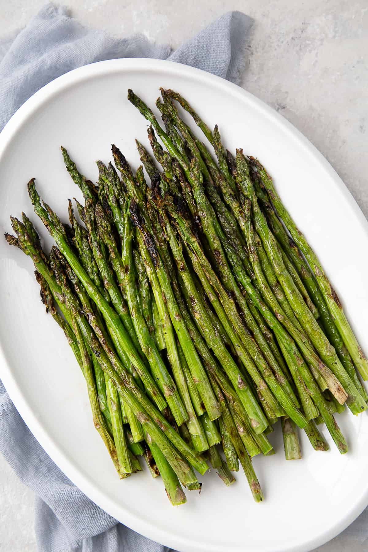 grilled asparagus on a white platter.
