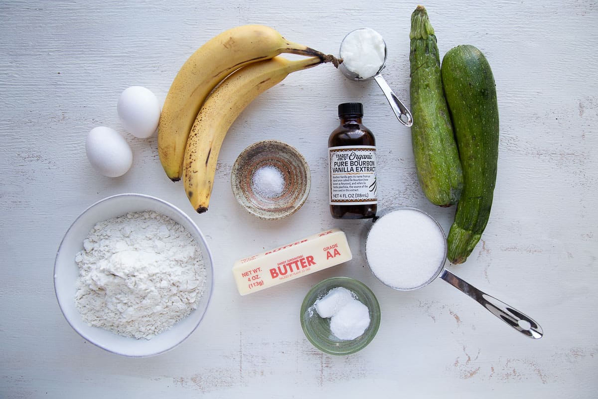 ingredients for zucchini banana bread on a white table.