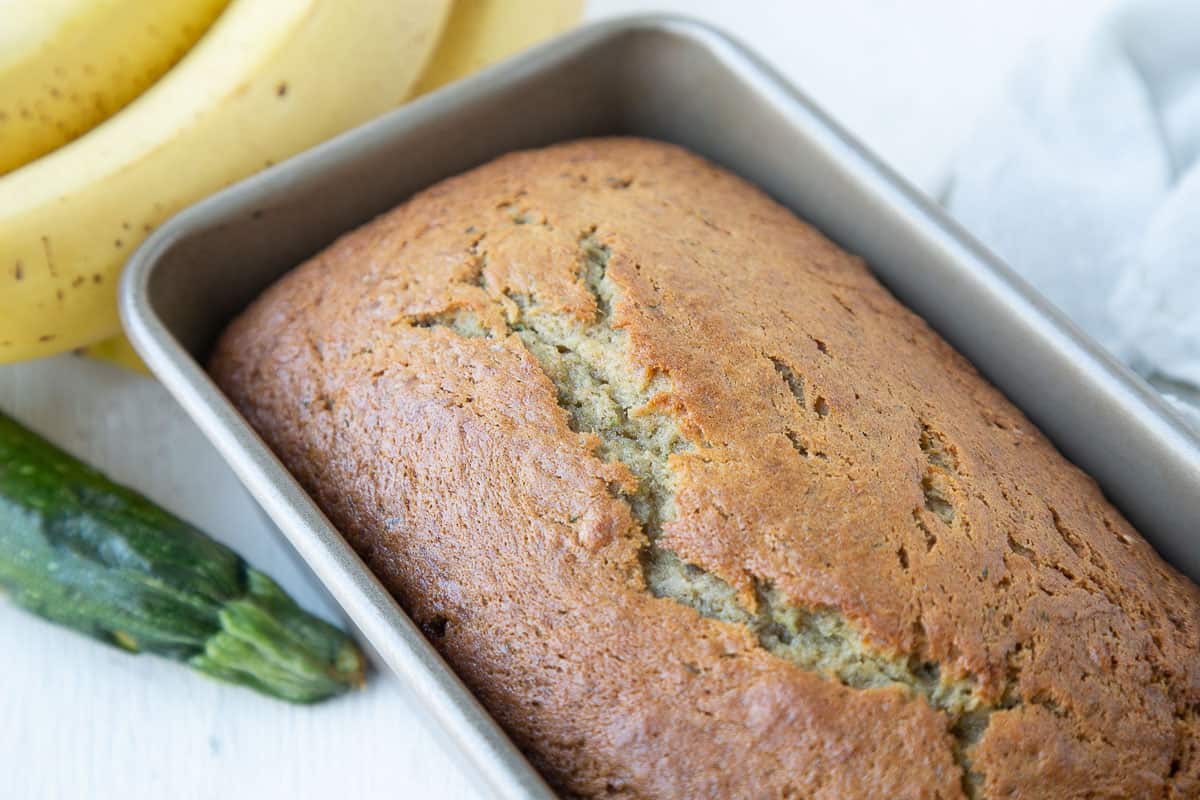 loaf of zucchini banana bread in a silver loaf pan.