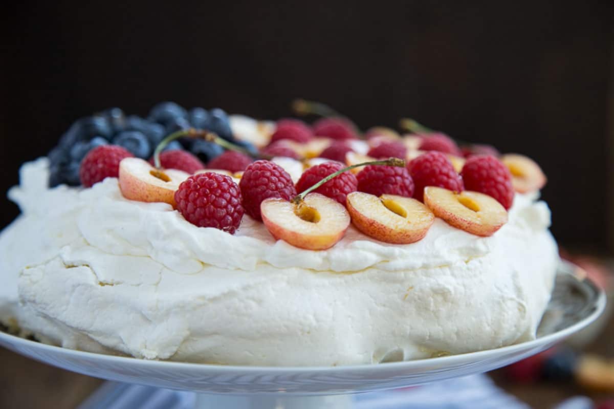 side of a pavlova, topped with whipped cream and berries.