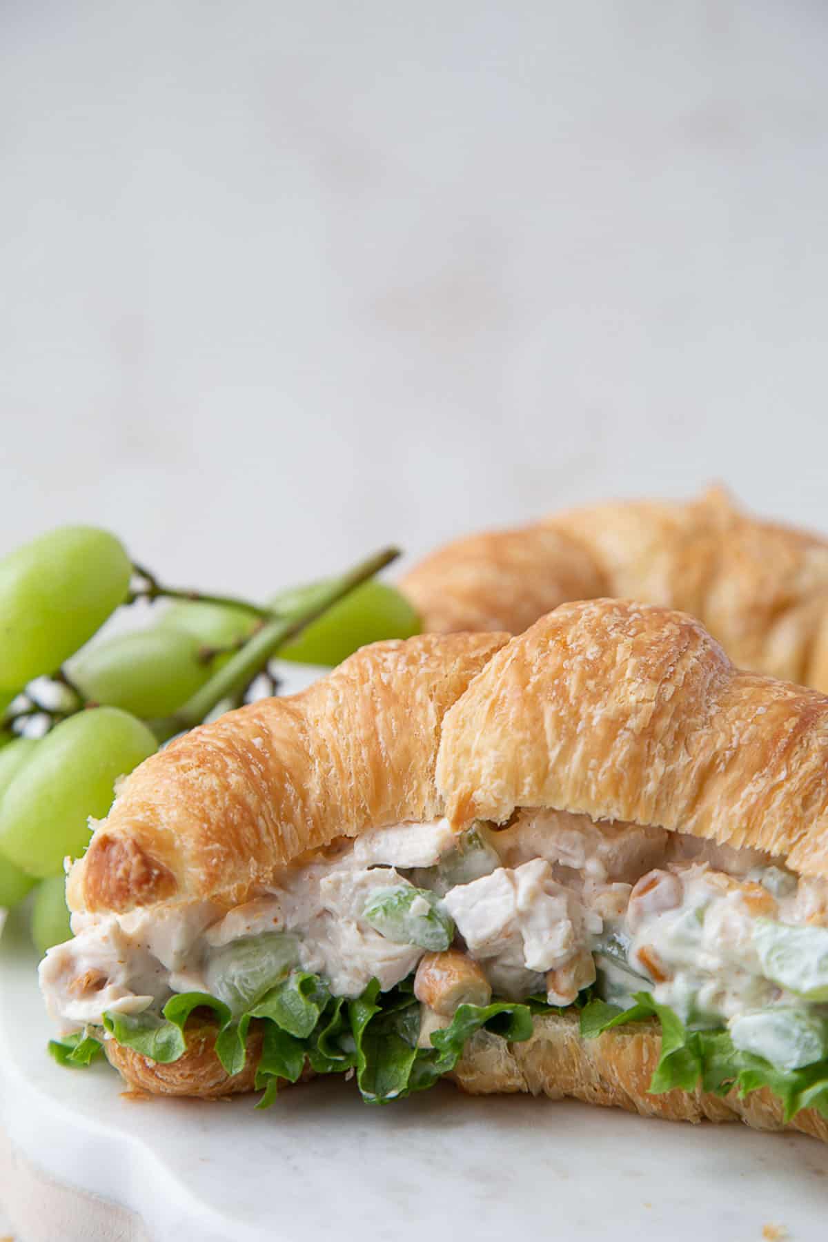 chicken salad with grapes and cashews on a croissant with green butter lettuce.