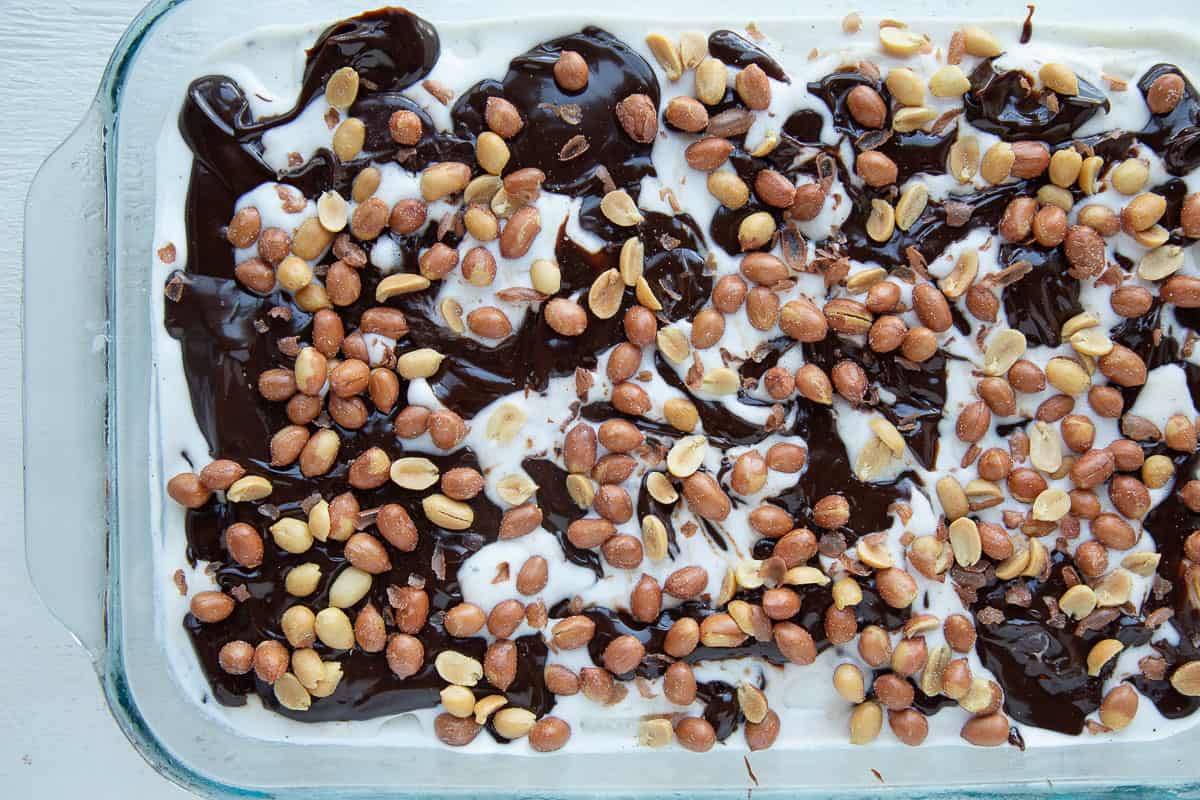 ice cream layered with chocolate fudge and spanish peanuts in a casserole dish.