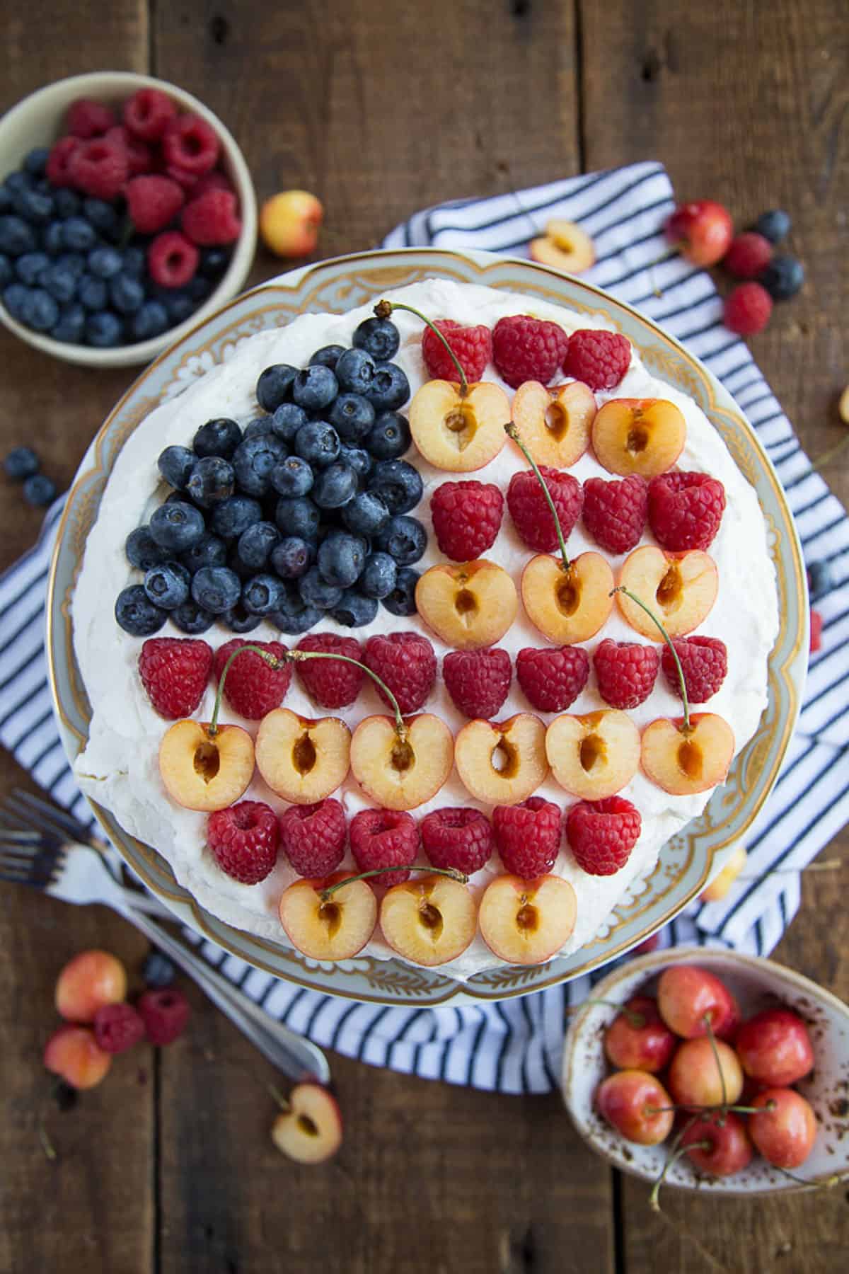 pavlova topped with berries and cherries in an american flag design.