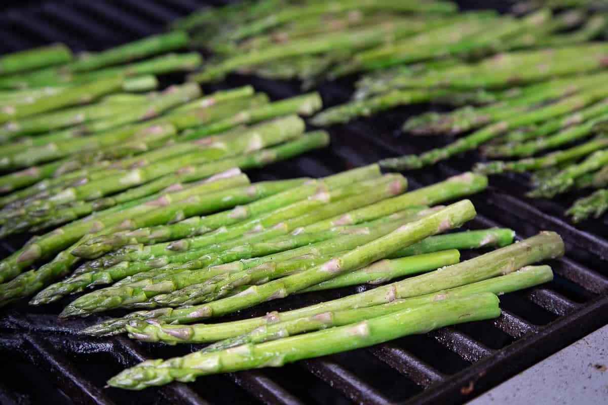 raw asparagus lined up on a grill.