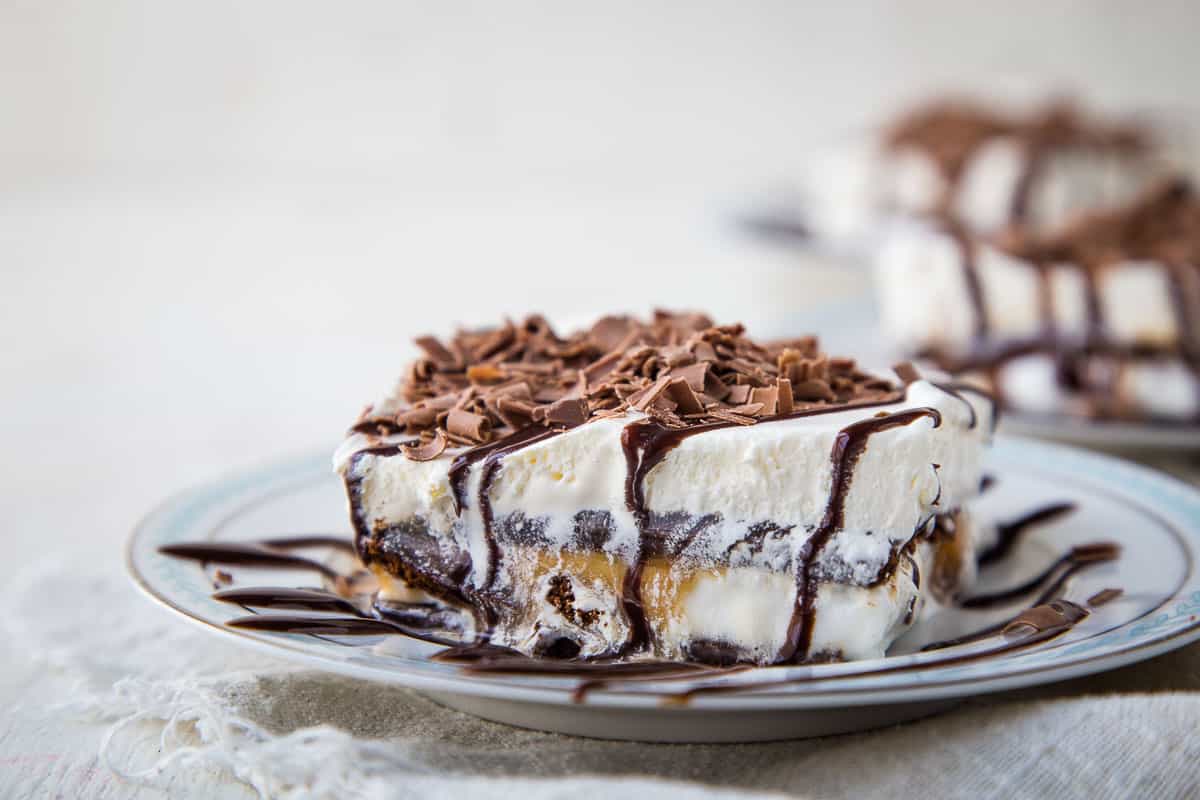 slice of an ice cream sandwich dessert topped with chocolate sauce and chocolate curls.