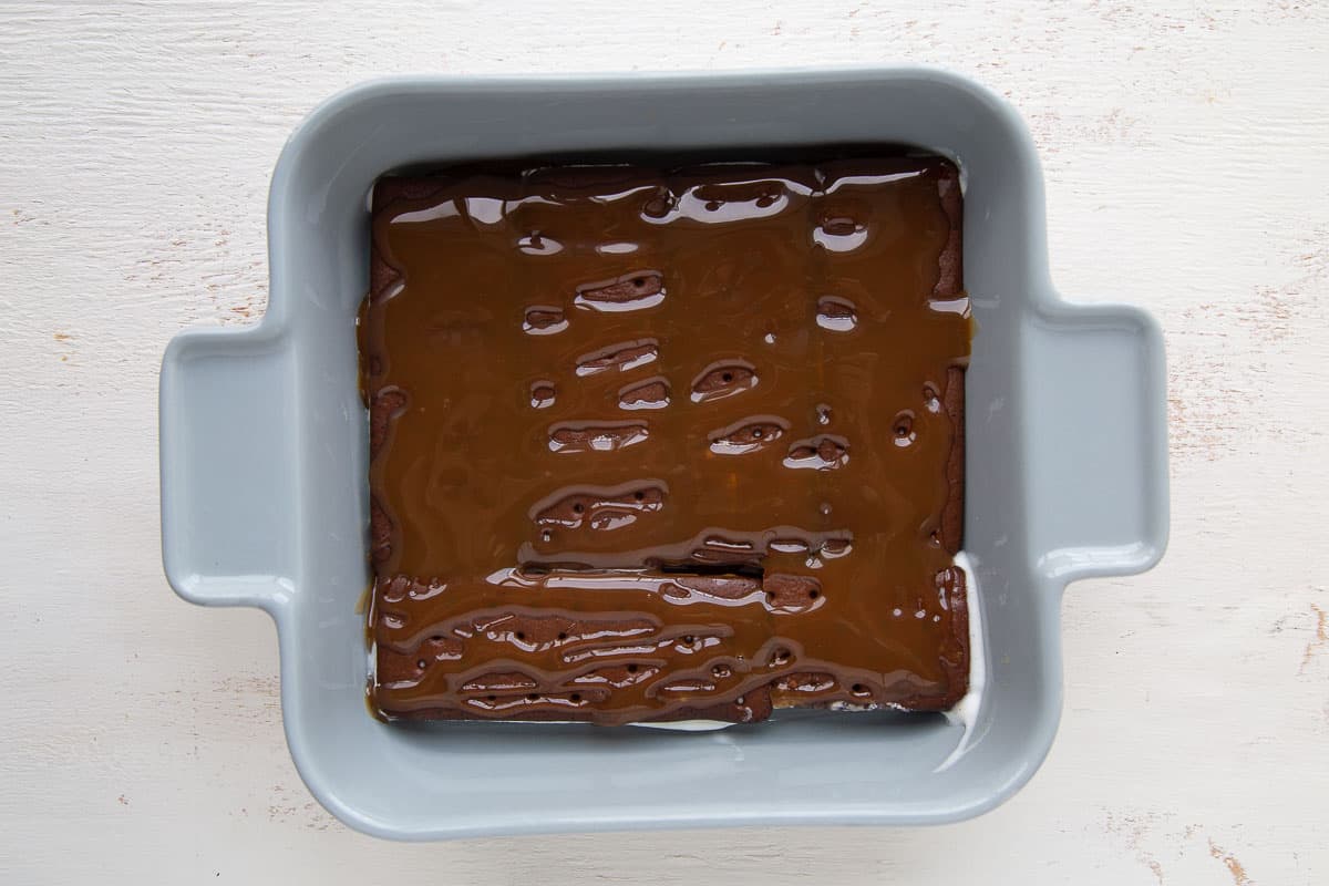 ice cream sandwiches topped with caramel sauce in a square casserole dish.