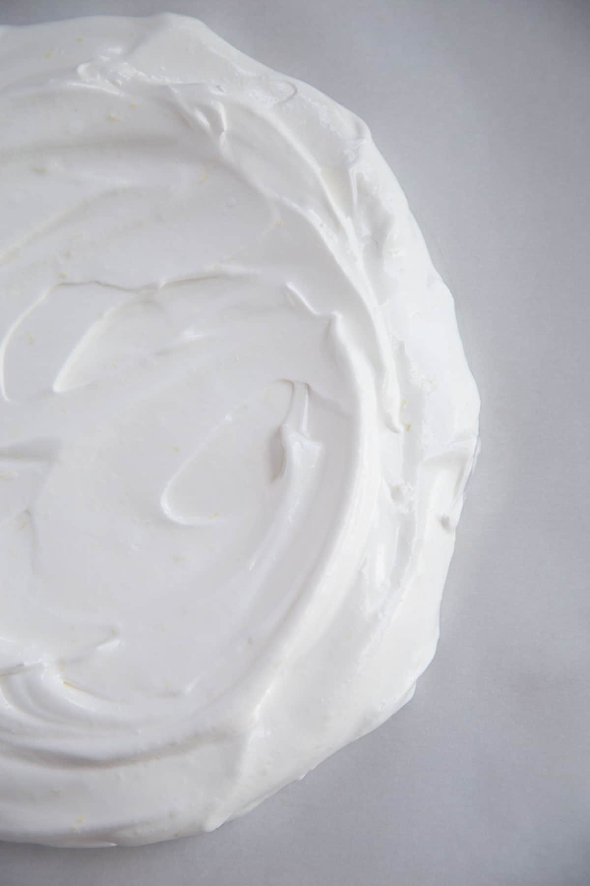 whipped egg whites in a circular shape on a piece of parchment paper.
