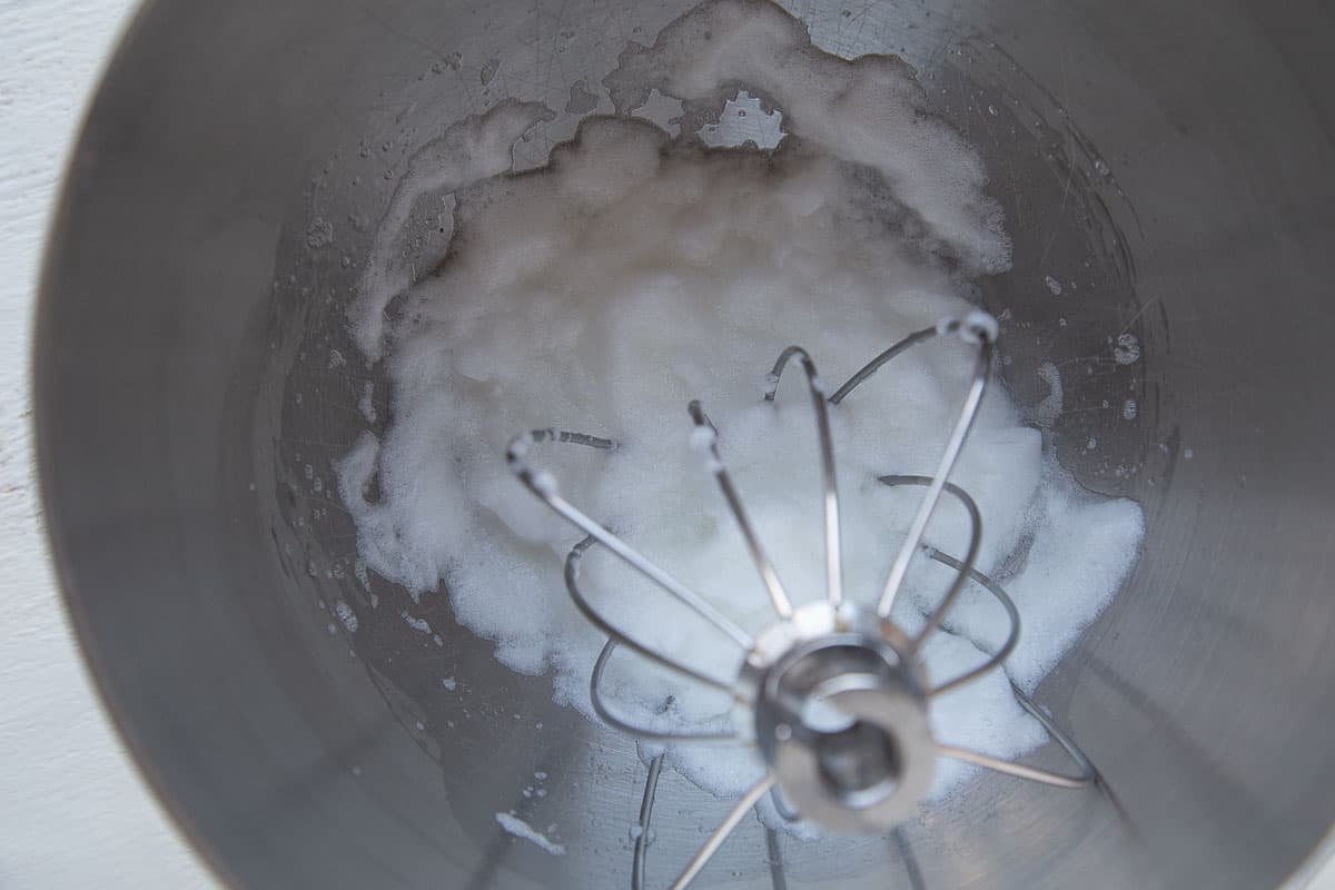 egg whites and a beater in a metal bowl.