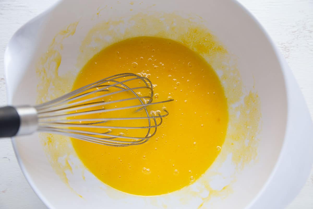 egg mixture in a white bowl with a whisk.