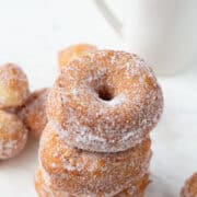 3 biscuit donuts stacked next to donut holes and a mug of black coffee.