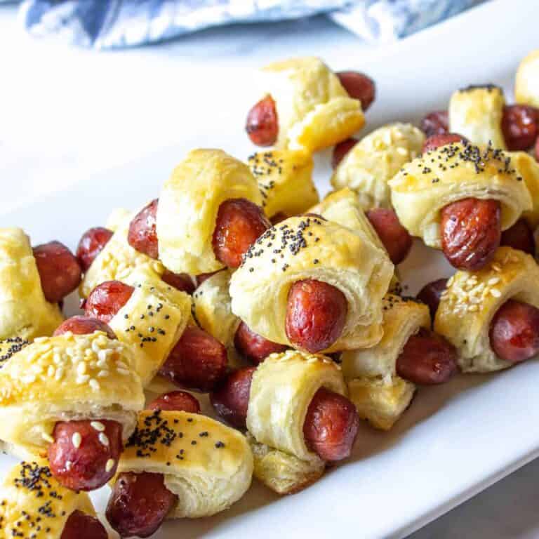 pigs in a blanket on a white platter.