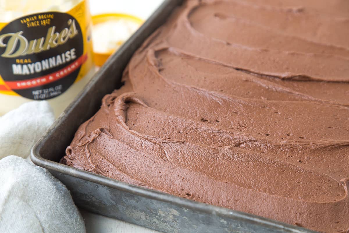 chocolate frosted cake next to a jar of mayonnaise.