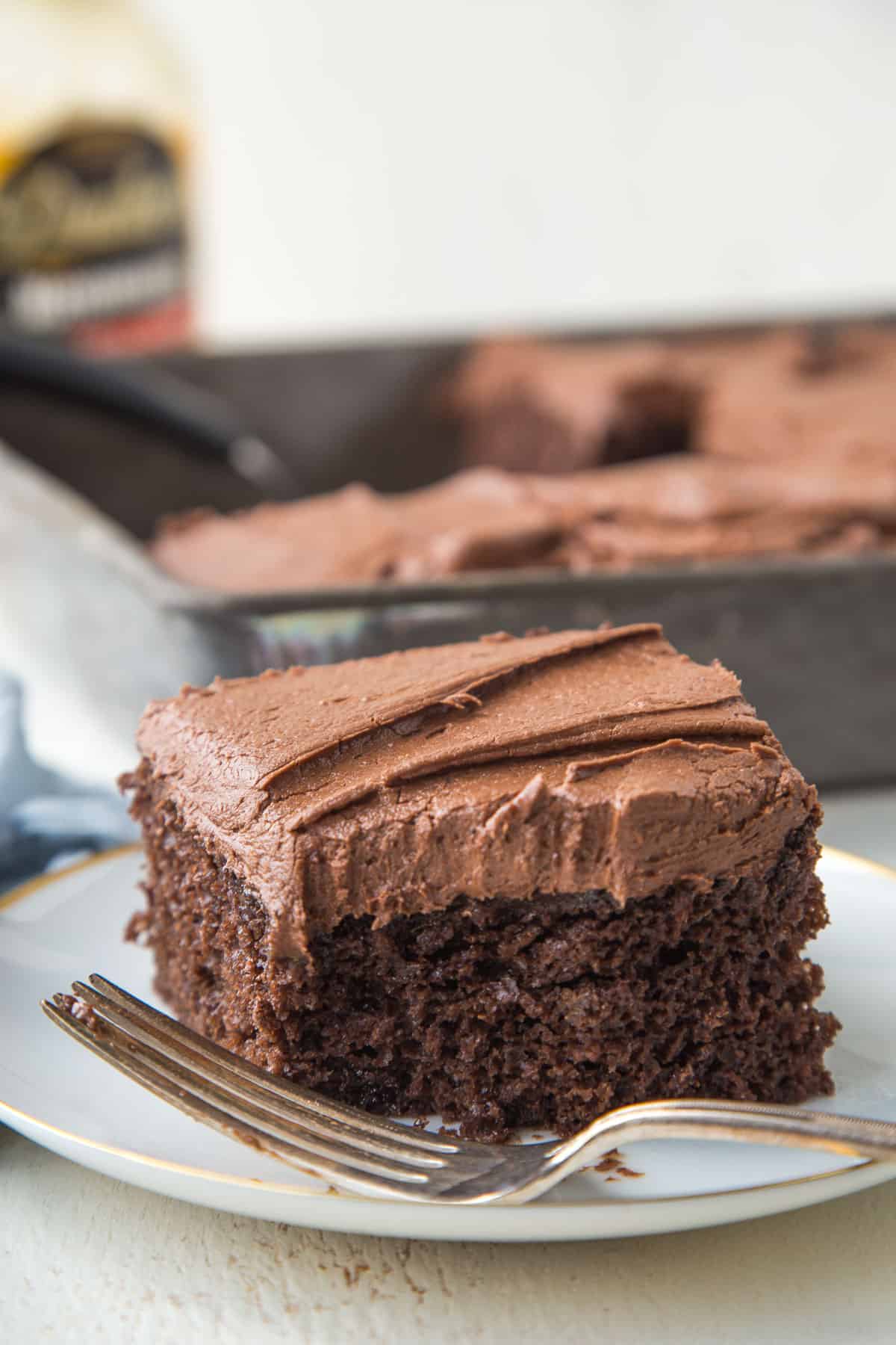 slice of chocolate mayonnaise cake on a white plate with a bite taken out.