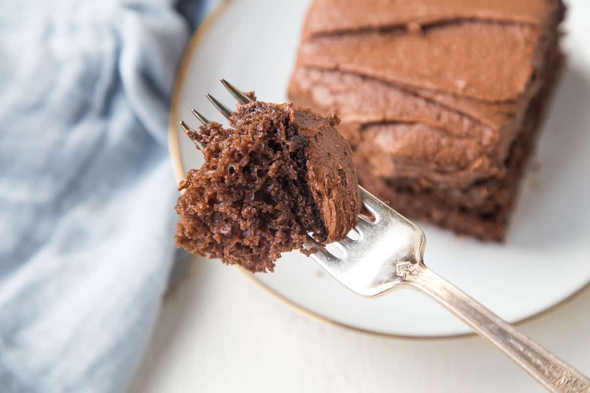 a fork holding up a bite of chocolate mayo cake with chocolate frosting.