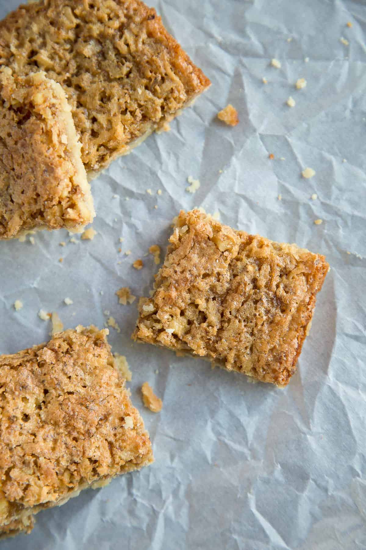 chewy coconut bar cookies on crumpled white parchment paper.