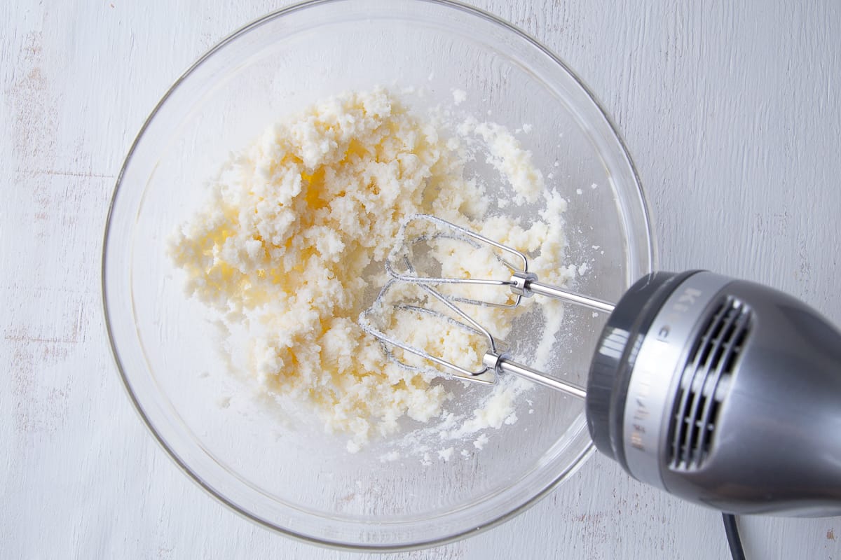 butter and sugar creamed together in a glass bowl with a hand mixer.