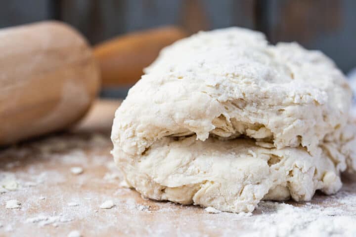 biscuit dough folded in half on a wooden board.