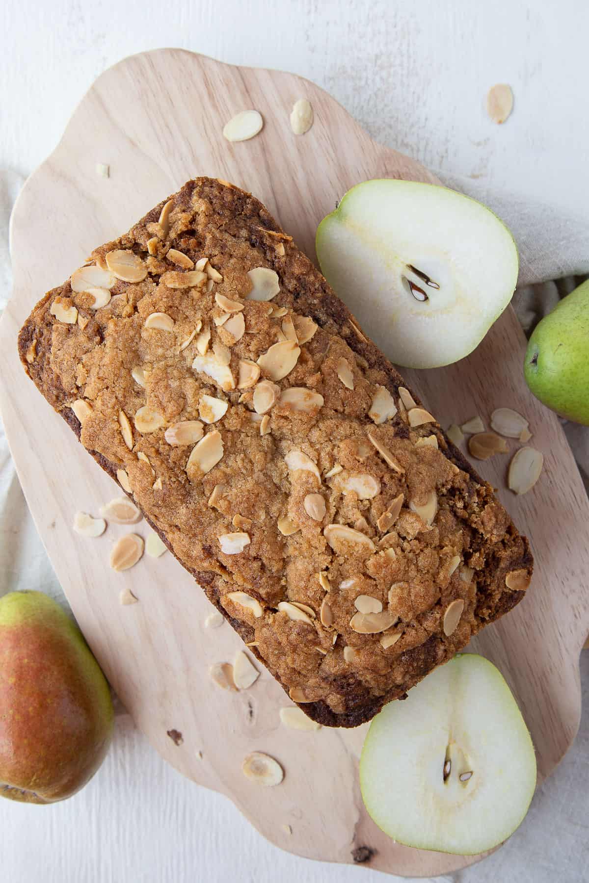 whole loaf of pear bread with candied ginger on a wooden cutting board.