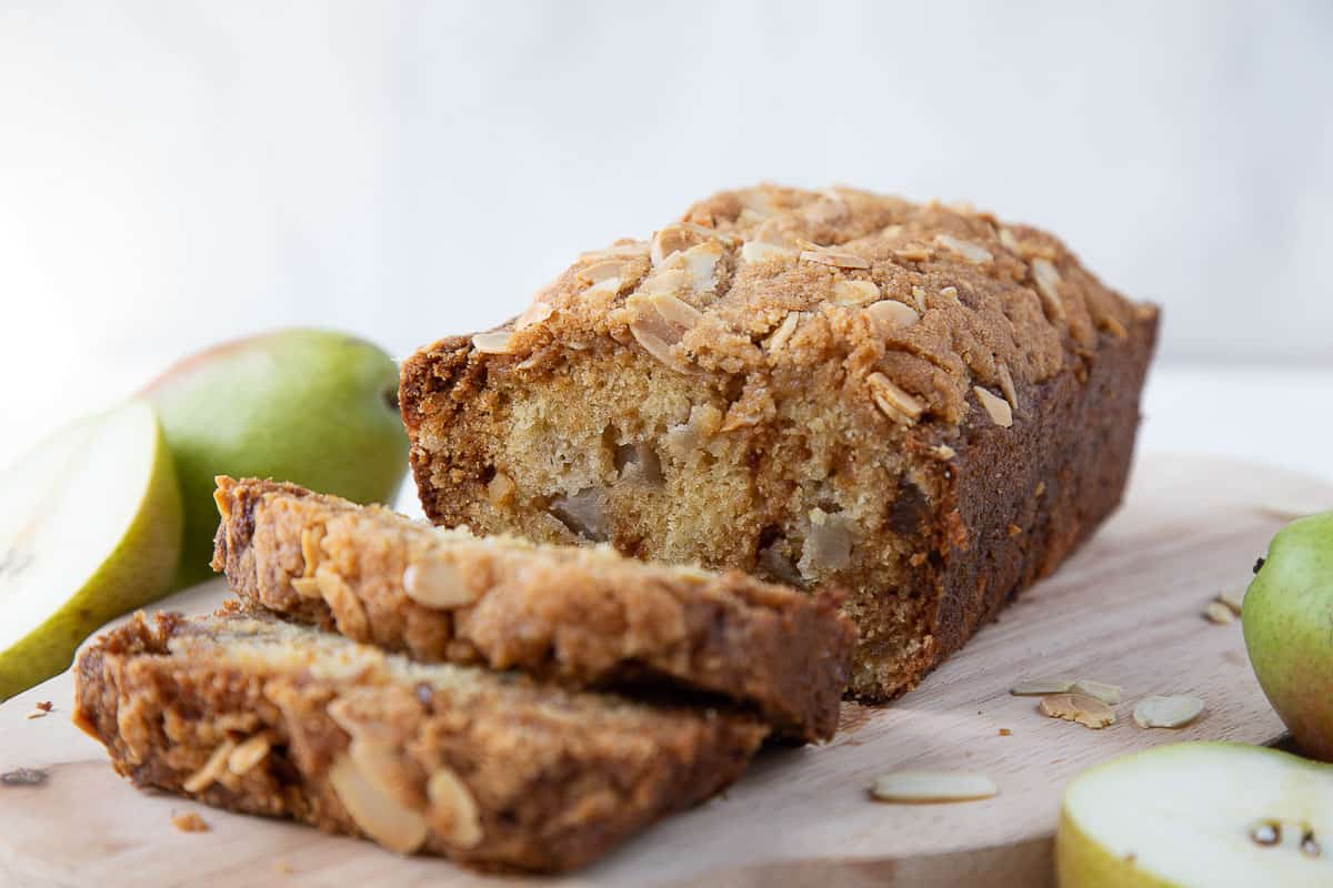 pear bread with slices taken out on a wooden board.