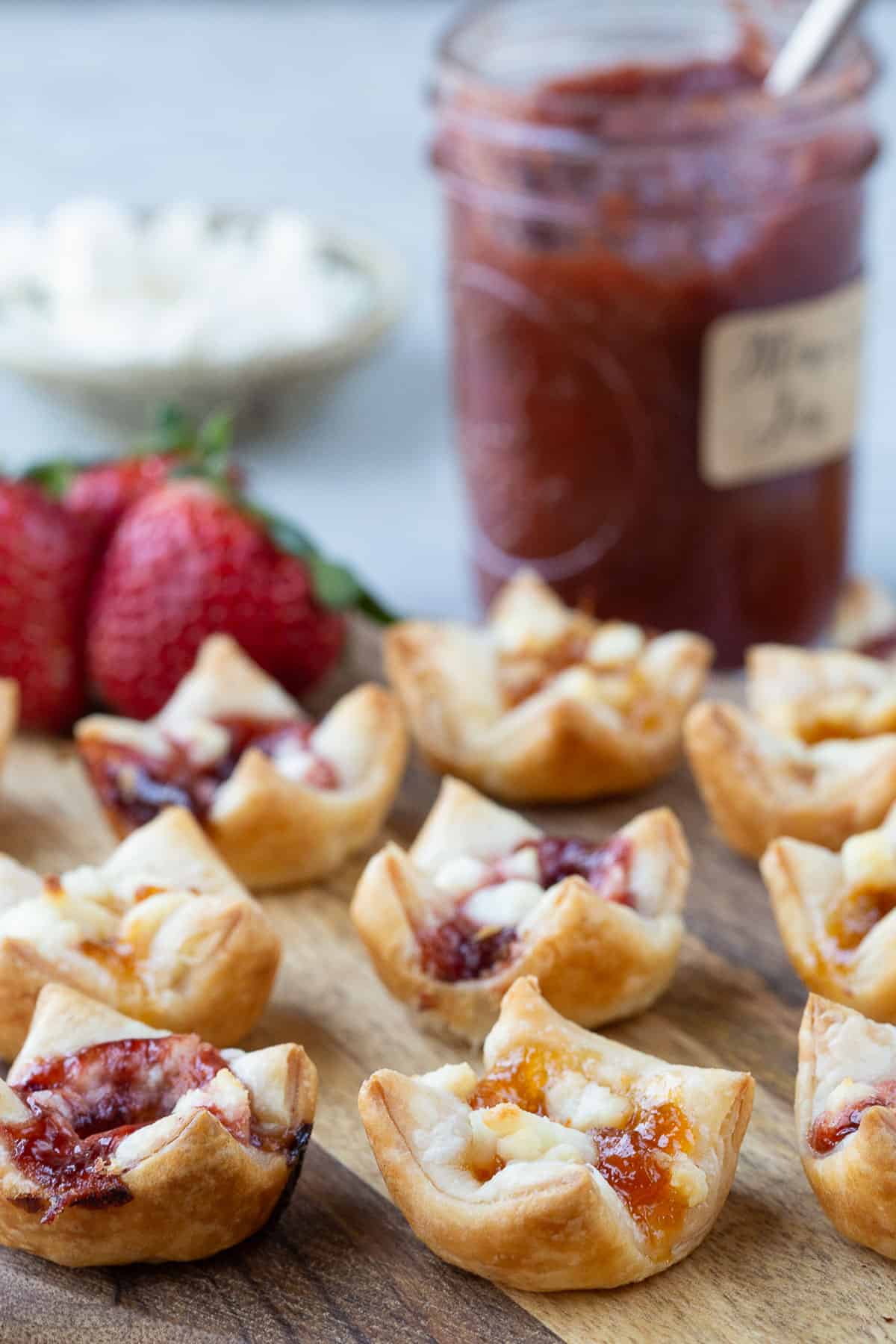 bite size puff pastry appetizers with goat cheese and jam next to a jar of jam.