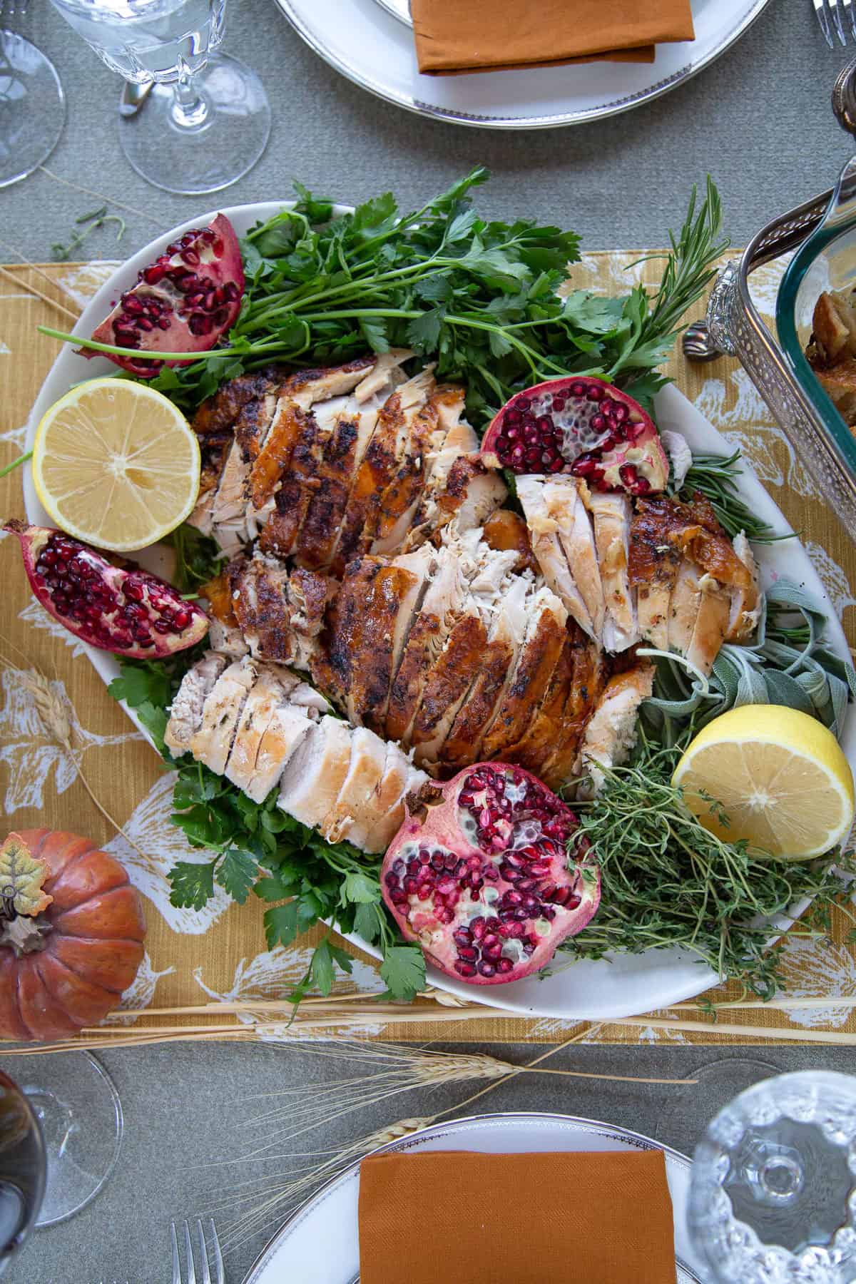 sliced turkey breast on a platter garnished with lemon halves and pomegranates.