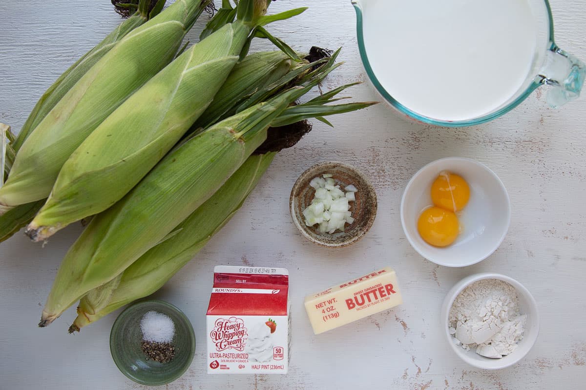 sweet corn, butter, milk, cream, and other ingredients on a white table.