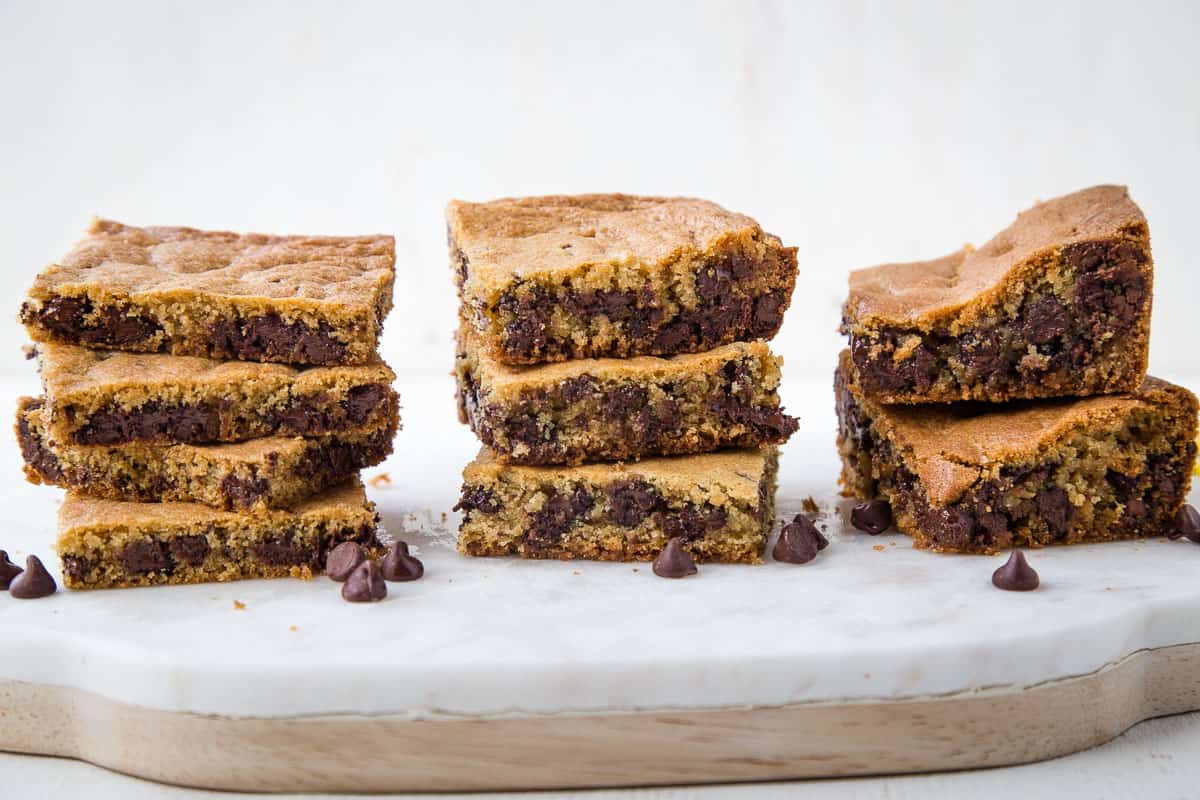 three stacks of toll house cookie bars in varying thicknesses on a marble and wooden platter.