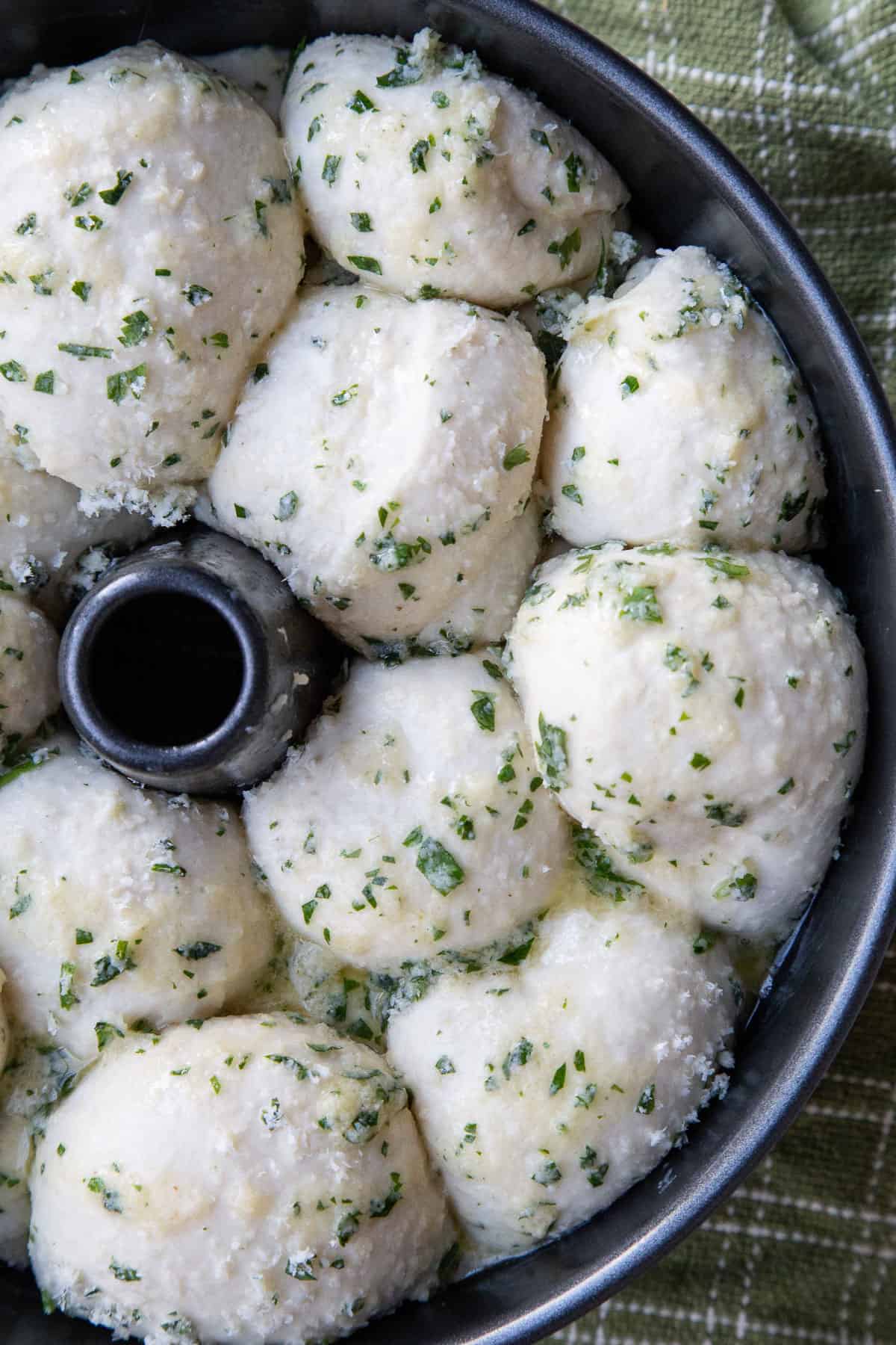 puffy dough balls, covered with parmesan and parsley, in a tube pan.