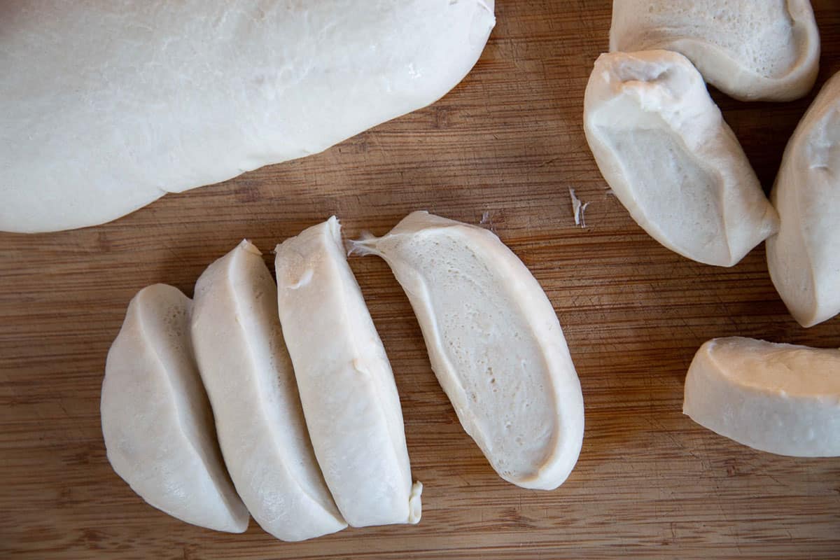 bread dough cut into small strips on a wooden cutting board.