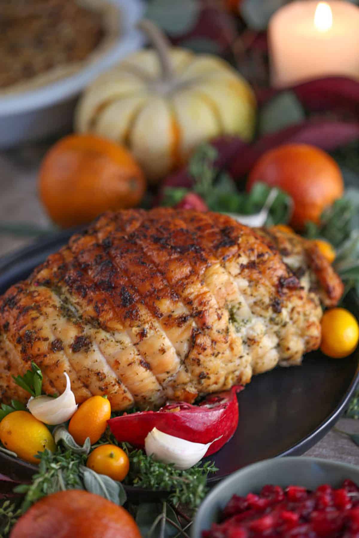 turkey breast on a platter surrounded by blood oranges, kumquats, and mini pumpkins.