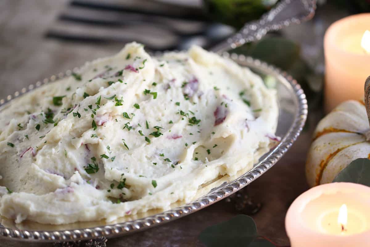 oval dish of mashed potatoes next to pillar candles.