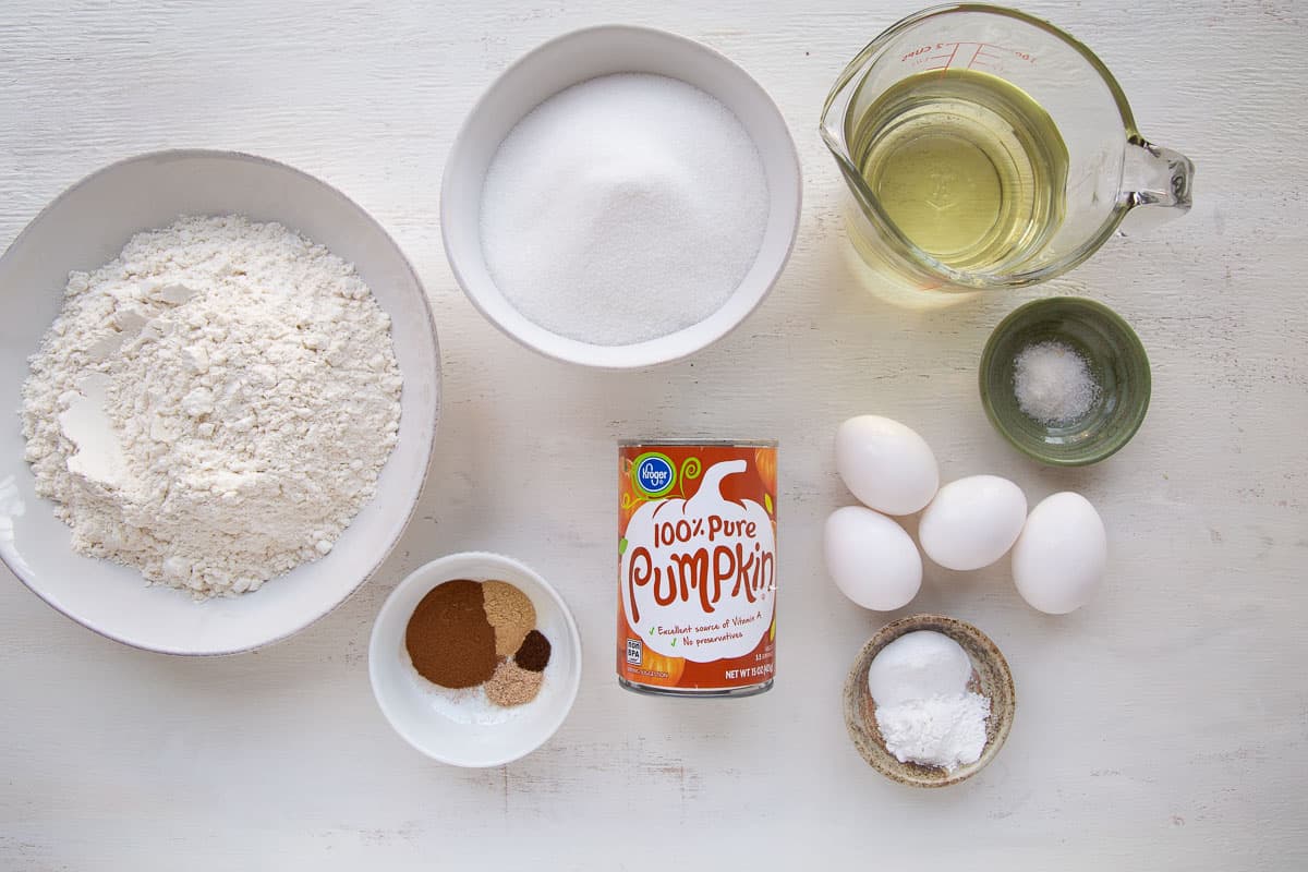 flour, sugar, oil, eggs, and other cake ingredients on a white table.