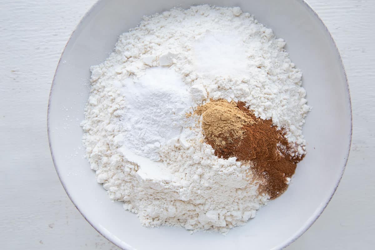 flour, baking powder, baking soda, and warm spices in a low white bowl.