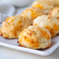 round biscuits with cheddar cheese on a white serving platter.