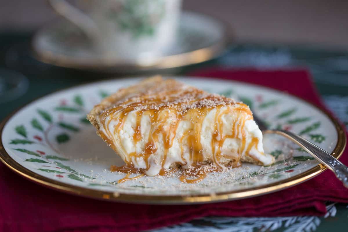 slice of eggnog pie with caramel drizzle on a christmas plate with holly and red berries.