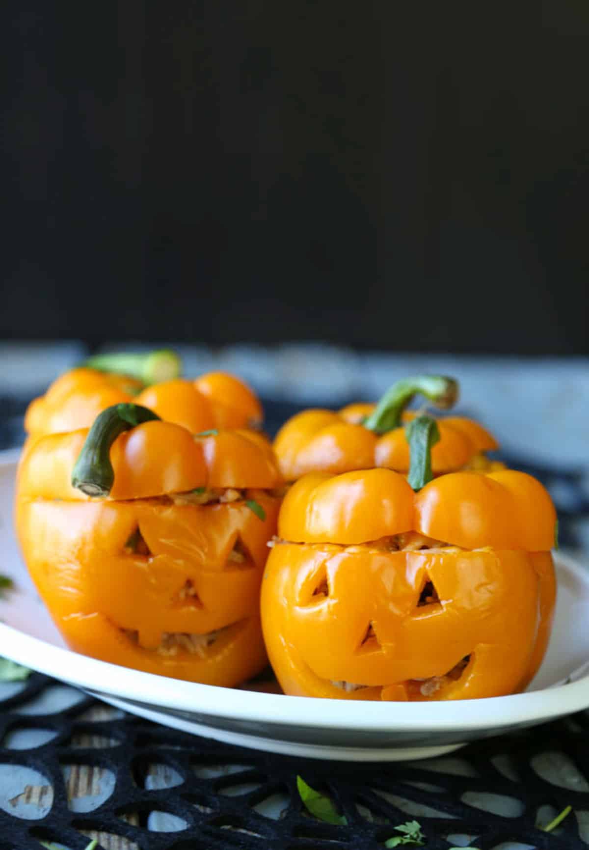 bell peppers with jack o'lantern faces on a white oval platter.