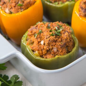 stuffed green pepper in a gray casserole dish with other stuffed bell peppers.