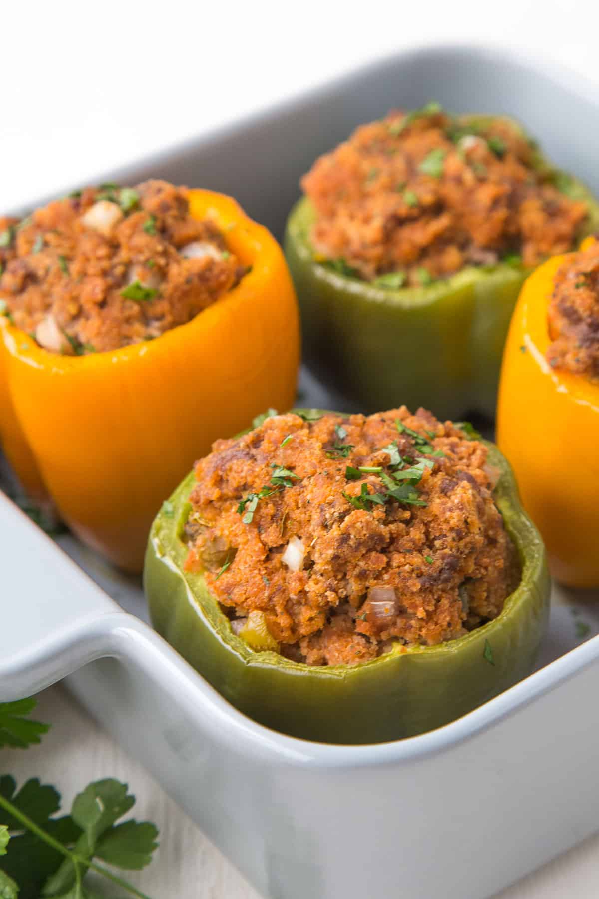 four beef stuffed bell peppers in a gray casserole dish.
