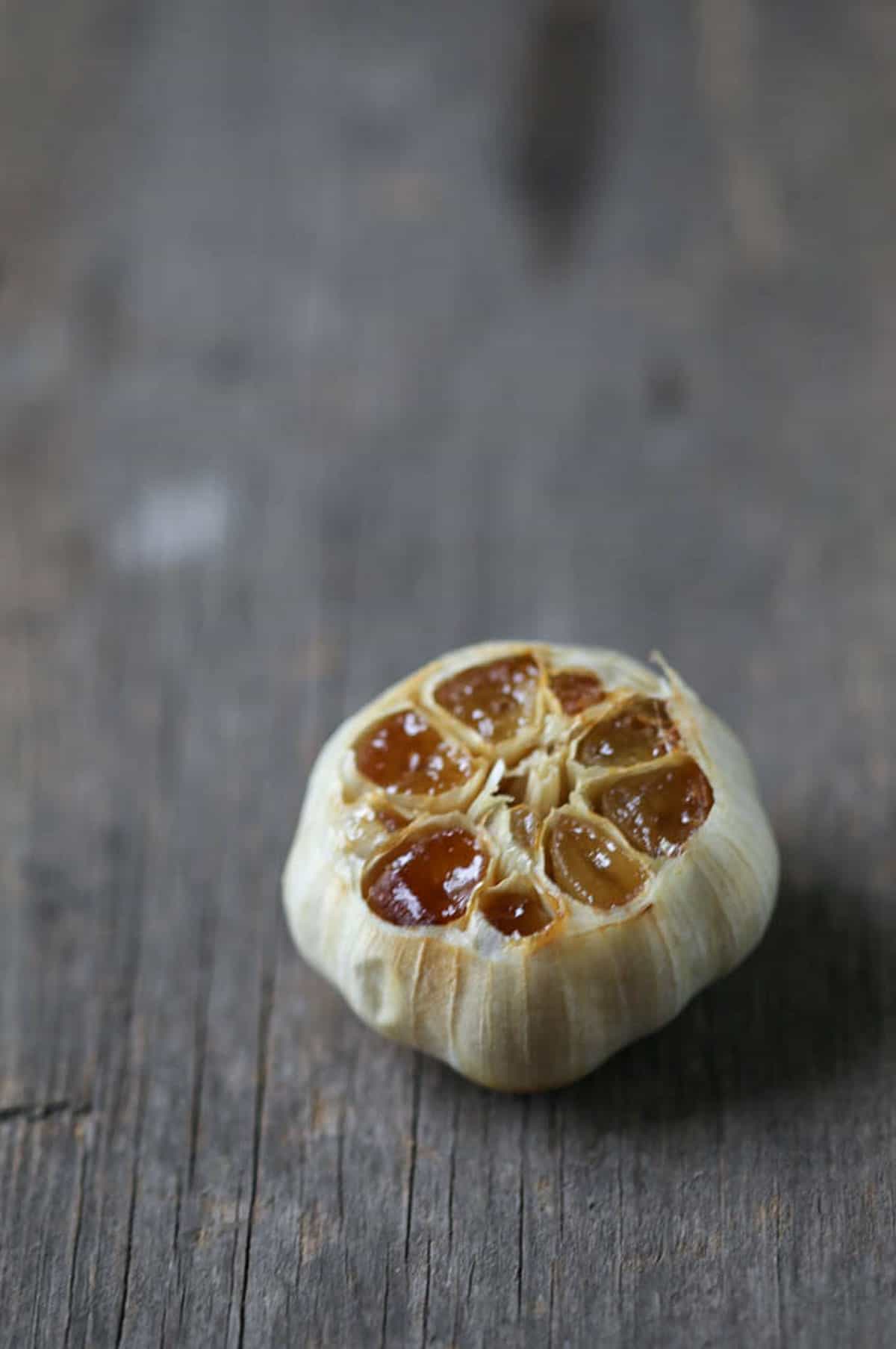 head of roasted garlic on a wooden board.