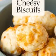 small biscuits with cheddar cheese inside in a green bowl.