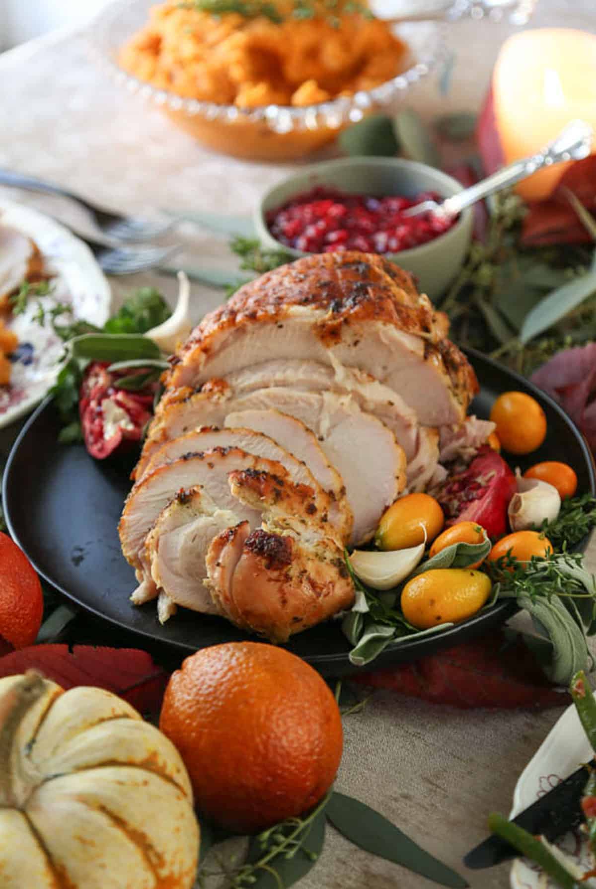 sliced turkey breast on a table with pumpkins and mashed sweet potatoes.