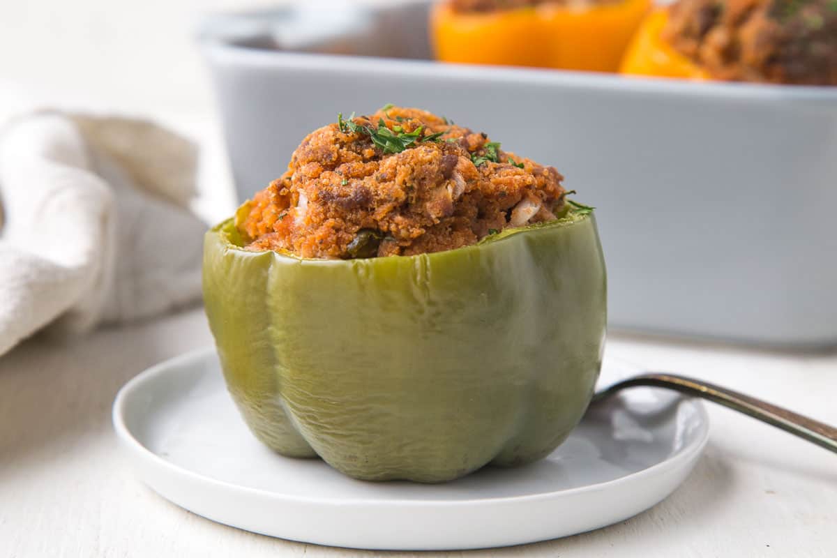 green stuffed bell pepper on a small white plate next to a fork.