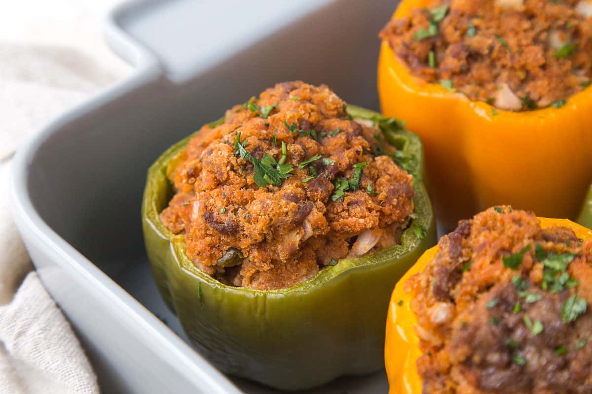 green and yellow stuffed bell peppers in a gray casserole dish.